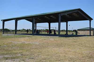 View of shaded volleyball court with game in play.